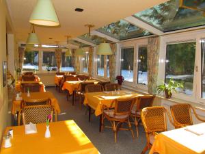 a restaurant with yellow tables and chairs and windows at Hotel Pension Marie-Luise, Hotel garni in Bad Bevensen