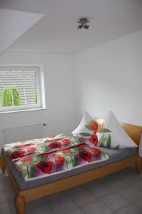 a bed with a colorful comforter and a window at Ferienwohnung An der Mühle in Nordholz