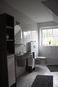 a white bathroom with a sink and a window at Ferienwohnung An der Mühle in Nordholz