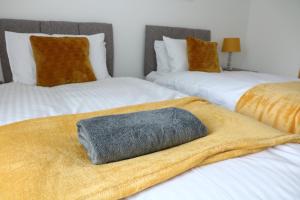 two beds with a towel on top of them at Ideal Lodgings in Bury - Whitefield in Bury