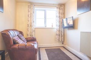 a living room with a leather chair and a window at Ibstock Self Catered Apartment in Ibstock