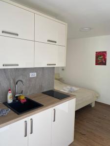 una cocina con armarios blancos y fregadero en Apartments Boss, en Budva