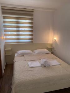 1 dormitorio con 2 camas, toallas y ventana en Apartments Boss en Budva