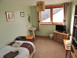 1 dormitorio con cama, lavabo y TV en Invicta House B&B, en Golspie