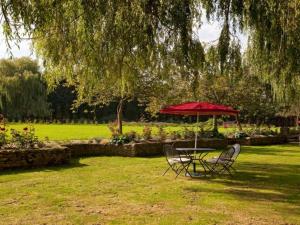 a table and chairs under a red umbrella in a park at Cherbridge Lodges - Riverside lodges, short lets (business or holidays) in Oxford