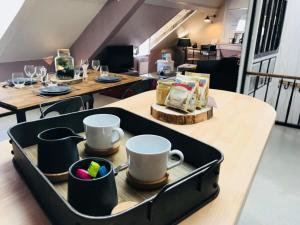 - une table avec un plateau pourvu de tasses et de vaisselle dans l'établissement La Fabrique Cherbourgeoise - Les Loges Normandes, à Cherbourg en Cotentin