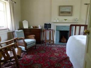 a bedroom with a bed and a chair and a fireplace at Iolanthe in London