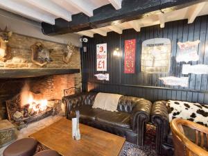 a living room with a leather couch and a fireplace at The Plough Bicester in Bicester