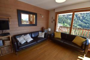 a living room with a leather couch and a balcony at VAUJANYLOCATIONS - Le Jardin Alpin in Vaujany