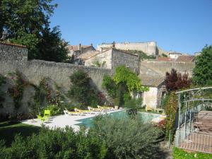 a garden with chairs and a swimming pool in front of a wall at Les Jardins De La Livrée in Villeneuve-lès-Avignon