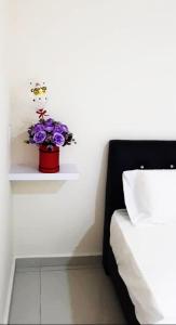 a vase of purple flowers on a shelf in a room at 28 Gred Hotel in Bukit Mertajam