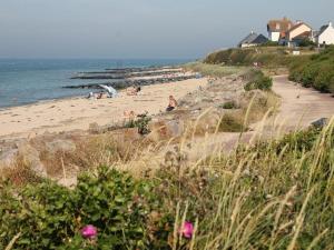 a beach with people on the sand and the ocean at Duplex Croisette Juno Beach in Bernières-sur-Mer