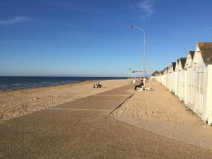 a beach with a fence and people sitting on benches at Duplex Croisette Juno Beach in Bernières-sur-Mer