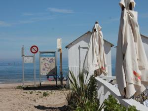 - deux parasols blancs assis sur une plage dans l'établissement Duplex Croisette Juno Beach, à Bernières-sur-Mer