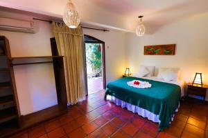 een slaapkamer met een bed met een groene deken bij Pousada Enseada Dos Golfinhos in Pipa