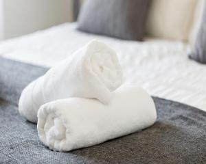 a pile of white towels on a bed at KCS Luxury Apartment - Broad Street Birmingham in Birmingham
