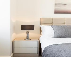 1 dormitorio con cama y mesita de noche con lámpara en KCS Luxury Apartment - Broad Street Birmingham, en Birmingham