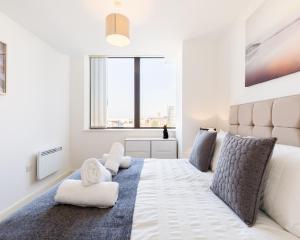 sypialnia z dużym białym łóżkiem i dużym oknem w obiekcie KCS Luxury Apartment - Broad Street Birmingham w Birmingham