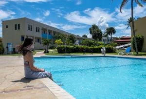 
a woman sitting on a balcony in front of a swimming pool at Parador El Faro in Aguadilla
