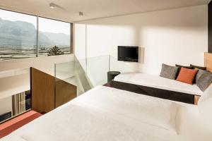 a bedroom with two beds and a large window at Hotel Traminerhof in Termeno