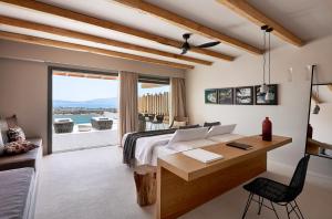 a bedroom with a bed and a desk and a window at Cave Suites Milos in Adamantas