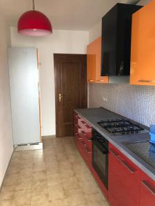 uma cozinha com armários vermelhos e um forno com placa de fogão em Appartamento Gemma em Martinsicuro