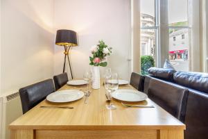 une table en bois avec des assiettes et des verres et un vase de fleurs dans l'établissement Host & Stay - Club Chambers, à Great Malvern