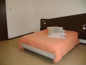 a bed with an orange blanket and a pillow at Hôtel Le Richevaux in Neufchâteau