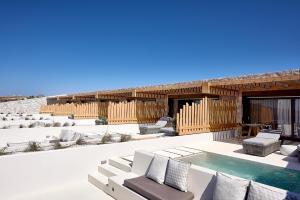 an outdoor patio with a pool and lounge chairs at Cave Suites Milos in Adamas