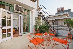 un patio al aire libre con mesa y sillas de color naranja en Prakash Kutir B&B en Nueva Delhi