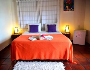 um quarto com uma cama com um cobertor vermelho e almofadas roxas em Pousada Enseada Dos Golfinhos em Pipa