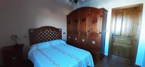 1 dormitorio con 1 cama y armario de madera en Pensión La Fuente, en Yegen