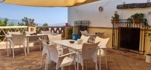 a restaurant with white tables and chairs on a patio at Pensión La Fuente in Yegen