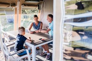 dos hombres y un niño sentados en una mesa de picnic en un remolque en Country Camp camping Begur, en Begur