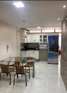 une salle à manger et une cuisine avec une table et des chaises en verre dans l'établissement Atlântico Flat - Apto 109, à Natal