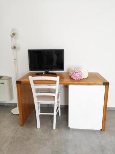 una scrivania in legno con TV e sedia bianca di A est b&b Otranto a Otranto