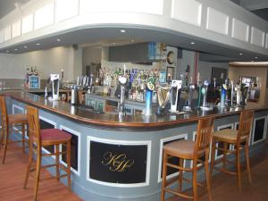 - un bar avec quatre chaises et un comptoir avec des boissons alcoolisées dans l'établissement The Kings Head, à Warrington