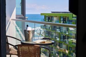 - une table avec des verres à vin et un livre sur un balcon dans l'établissement Rubic Apartment Spa n Pool beach Resort, à Mamaia Nord – Năvodari