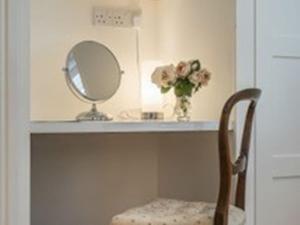 a counter with a mirror and a chair in a room at Knole B&B in Sevenoaks