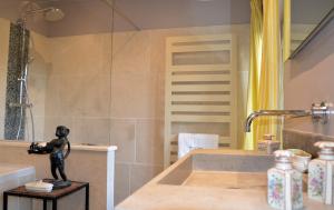 La salle de bains est pourvue d'une baignoire avec une statue sur un tabouret. dans l'établissement La Bastide des Enquèses, à Lorgues
