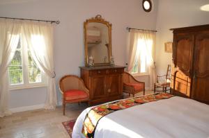 a bedroom with a bed and a mirror and chairs at La Bastide des Enquèses in Lorgues