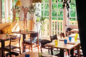 ein Restaurant mit Tischen, Stühlen und Fenstern in der Unterkunft La Cascade in Clisson