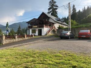 ein Haus mit zwei Autos, die davor geparkt sind in der Unterkunft Pensiunea Turistică Tihuța in Piatra Fântânele