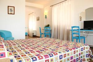 a bedroom with a bed with blue chairs and a table at Hotel O'scià in Lampedusa
