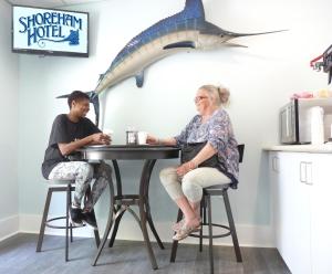 a man and woman sitting at a table with a shark head on the wall at Shoreham Oceanfront Hotel in Ocean City