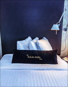 ein Bett mit weißer Bettwäsche und einem schwarzen Kissen darauf in der Unterkunft Solita Soho Hotel in New York