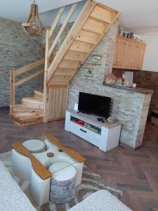 ein Wohnzimmer mit einem TV und einer Treppe in der Unterkunft Apartman Šumska Tajna in Mokra Gora