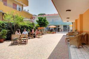 un groupe de personnes assises à des tables dans un patio dans l'établissement Hotel Nella, à Rimini