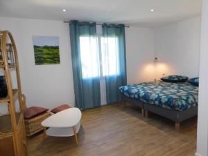 um quarto com uma cama, uma cadeira e uma janela em La Maison de Paul & Margaux em Châteauneuf-de-Galaure