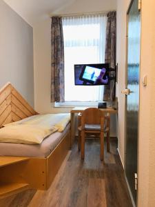 a bedroom with a bed and a chair and a television at Hotel Göbel in Aachen